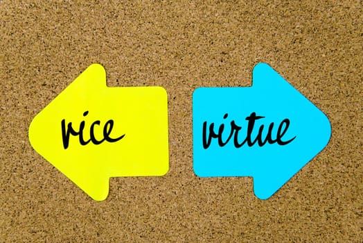 Message Vice versus Virtue on yellow and blue paper notes as opposite arrows pinned on cork board with thumbtacks. Choice conceptual image