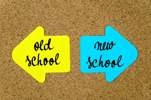 Message Old School versus New School on yellow and blue paper notes as opposite arrows pinned on cork board with thumbtacks. Choice conceptual image