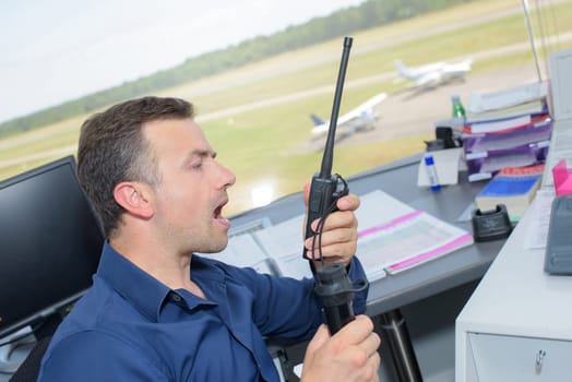 Man in control tower shouting into radio receiver