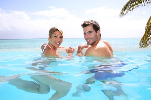 Cheerful couple swimming in infinity pool