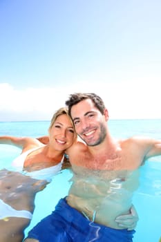 Cheerful couple swimming in infinity pool