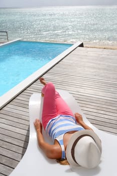 Woman relaxing in deck chair in front of the sea