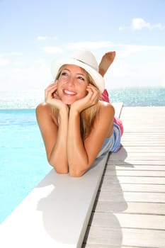 Beautiful trendy girl laying by pool on a sunny day