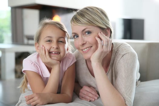 Portrait of mother and daughter laying in couch at home