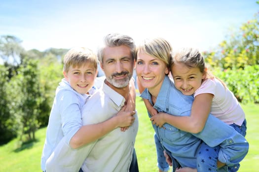 Parents giving piggyback ride to kids in garden