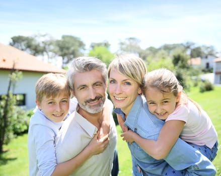 Parents giving piggyback ride to kids in garden