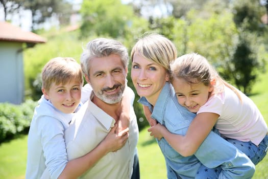 Parents giving piggyback ride to kids in garden