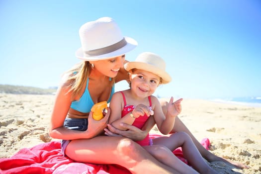 Woman applying sunscreen on daughter's body