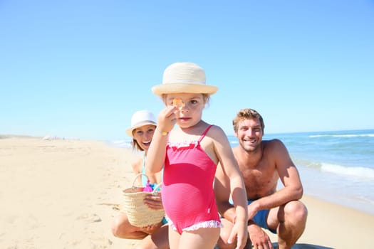 Parents with little girl playing on a sandy beach
