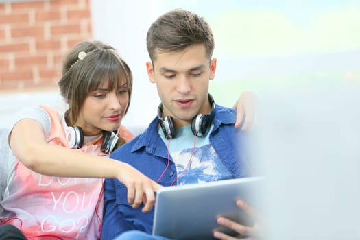 Young couple in sofa websurfing with tablet