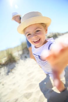Little girl pulling parents' arms to run to the beach