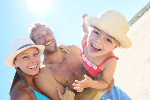 Cheerful parents holding little girl in arms at the beach