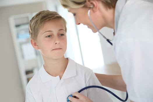 Doctor examining 12-year-old boy with stethoscope