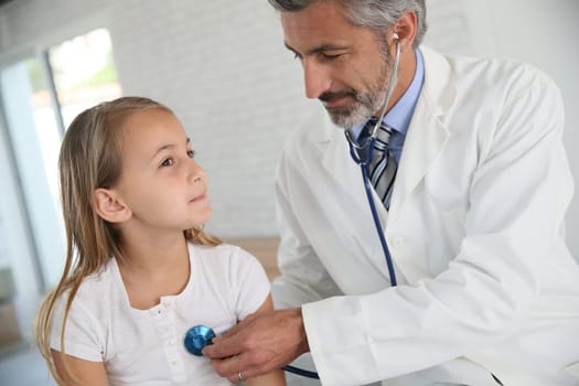 Doctor examining young girl with stethoscope