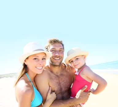 Cheerful parents holding little girl in arms at the beach