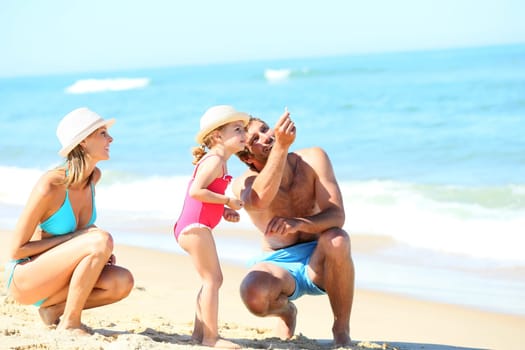 Parents with little girl playing on a sandy beach