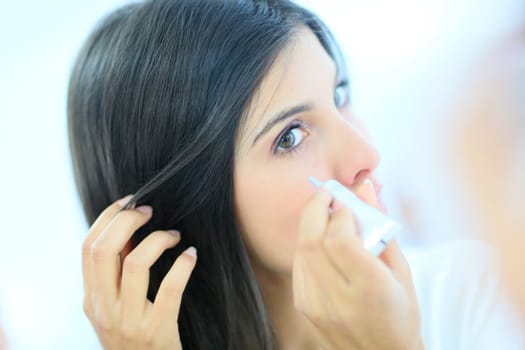 Beautiful brunette woman applying concealer