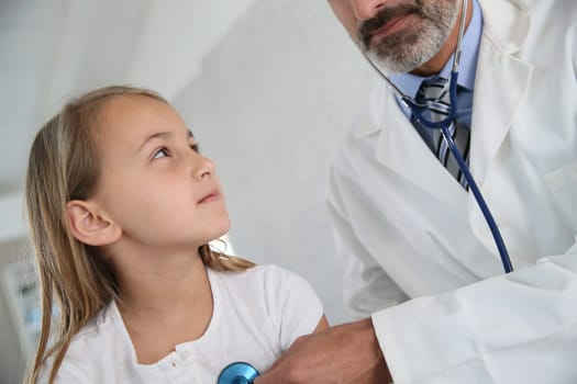 Doctor examining young girl with stethoscope