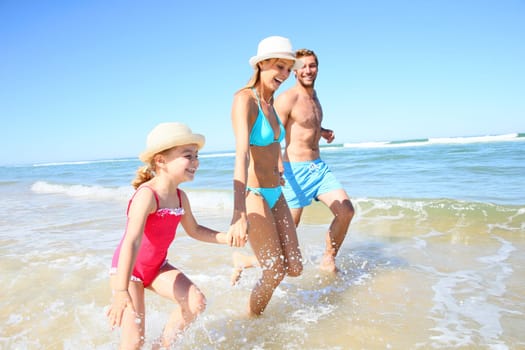 Family having fun running on a sandy beach