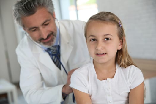 Doctor examining young girl with stethoscope