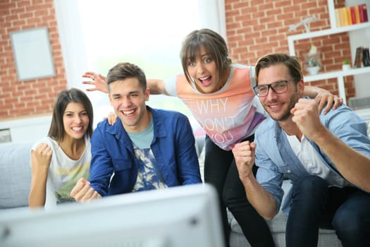 Cheerful group of friends watching football game on tv