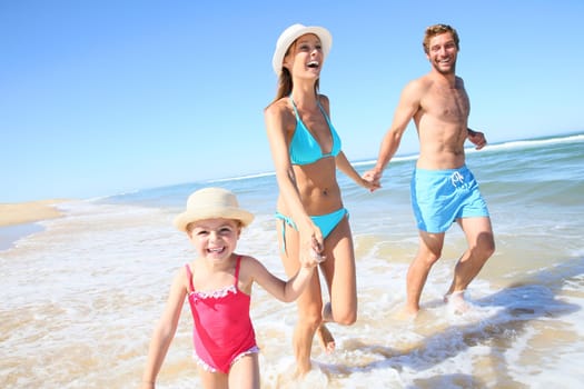 Family having fun running on a sandy beach