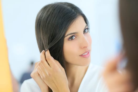 Portrait of beautiful young woman looking at her skin