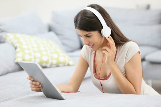 Young woman with tablet and headphones sitting on floor