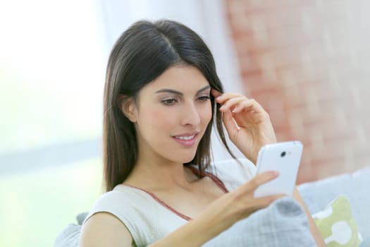Portrait of brunette girl using smartphone at home
