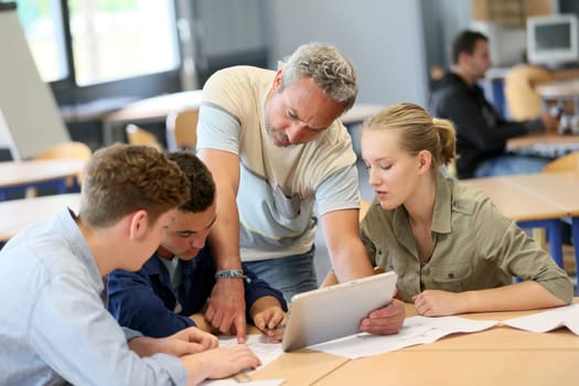 Teacher with group of students working on digital tablet