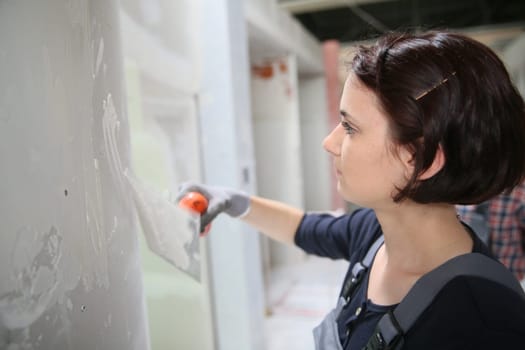 Young plasterer working on indoor wall
