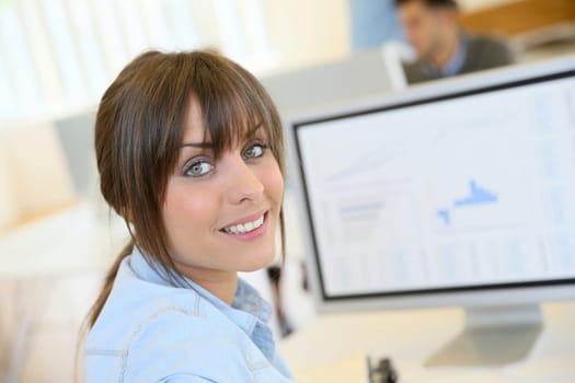 Portrait of cheerful office worker sitting in front of desktop