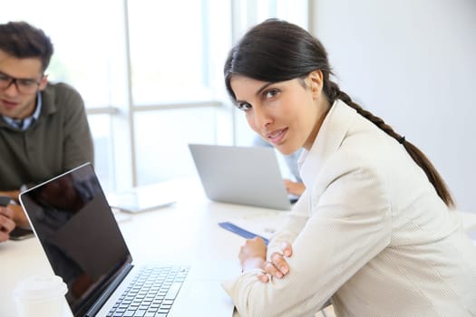 Businesswoman working on laptop, shared workspace