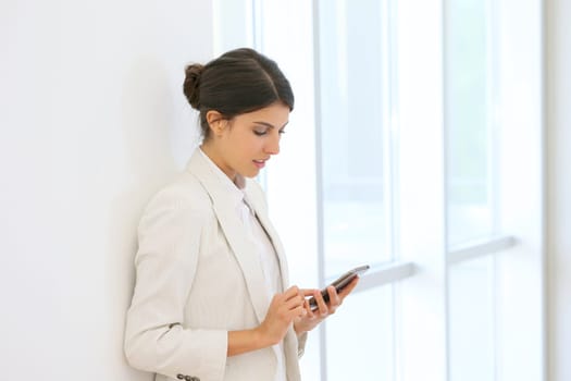 Executive woman using smartphone in hallway
