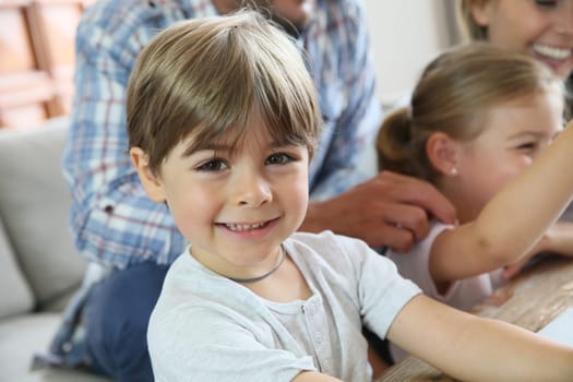 Portrait of smiling 4-year-old boy, family in background