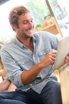 Young man at coffee shop connected on internet with tablet
