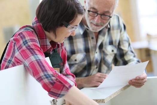 Young woman with senior craftsman in carpentry class