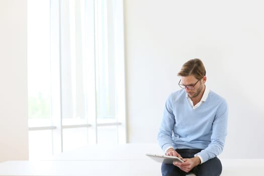 Man sitting on table, connected on digital tablet, white background