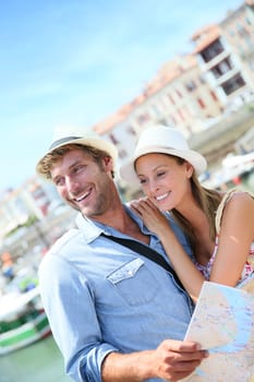 Couple of tourists at seaside resort looking at city map