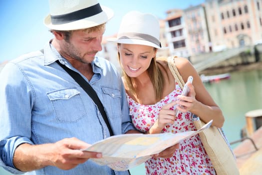 Couple of tourists at seaside resort looking at city map
