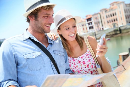 Couple of tourists at seaside resort looking at city map