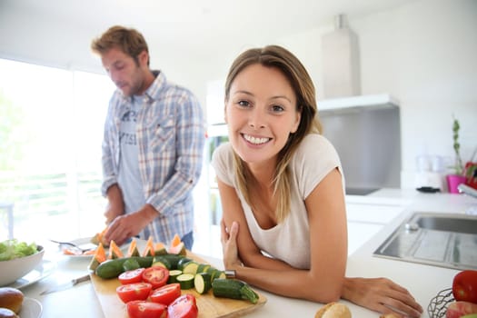 Portrait of cheerful woman in kitchen, boyfriend preparing lunch