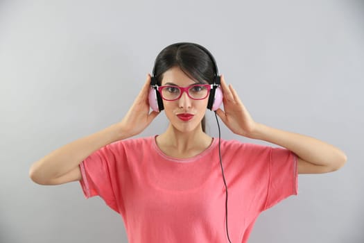 Clsoeup of brunette girl with eyeglasses using headphones