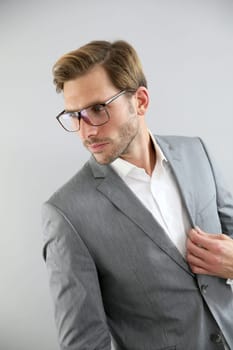 Businessman with eyeglasses standing on grey background, isolated