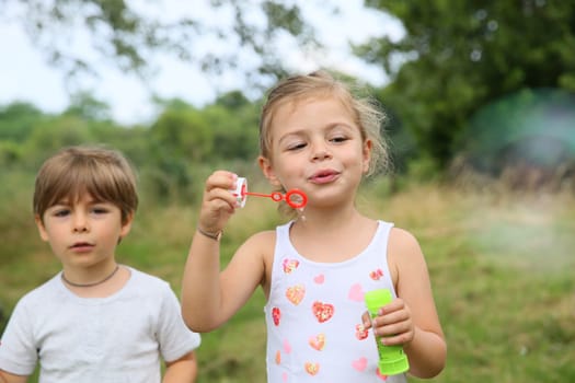 Kids in garden blowing soap bubbles