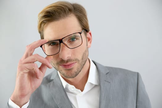 Businessman with eyeglasses standing on grey background, isolated