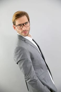 Businessman with eyeglasses standing on grey background, isolated
