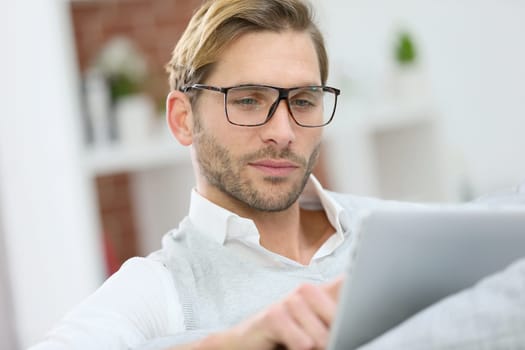 Man with eyeglasses connected on digital tablet at home