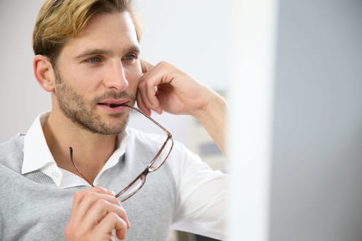 Businessman with eyeglasses sitting in front of desktop computer screen