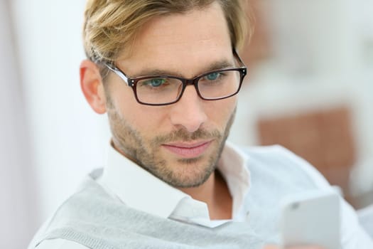 Man with eyeglasses reading message on smartphone